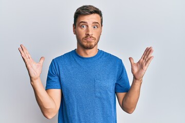 Fototapeta premium Handsome caucasian man wearing casual clothes clueless and confused with open arms, no idea and doubtful face.