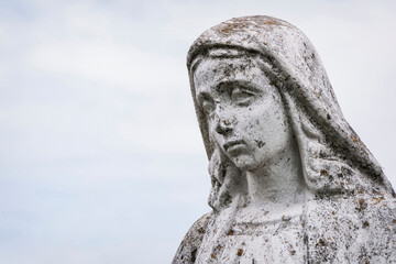 Obraz premium A old sculpture of Virgin Mary. The stone statue is partially destroyed by time. (faith concept)