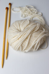 soft white knitting yarn and brown wooden needles