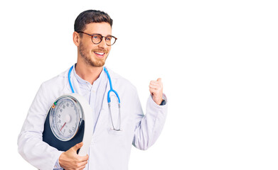 Handsome young man with bear as nutritionist doctor holding weighing machine pointing thumb up to the side smiling happy with open mouth