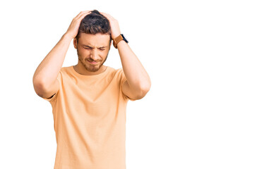 Handsome young man with bear wearing casual yellow tshirt suffering from headache desperate and stressed because pain and migraine. hands on head.