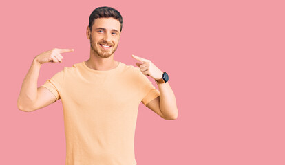 Handsome young man with bear wearing casual yellow tshirt smiling cheerful showing and pointing with fingers teeth and mouth. dental health concept.