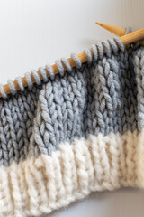 grey and white knitting fabric on needles with copy space 