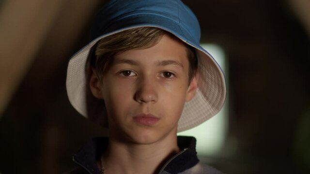 portrait of a serious boy in a blue hat looking at the camera, moving camera, indoors