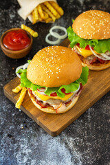 Delicious burgers with cutlet beef, bacon, french fries and ketchup on a slate table. Copy space.