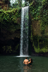 Lovers at the waterfall. Couple admiring a beautiful waterfall in Indonesia. Couple on vacation in Bali. Honeymoon trip. The couple is traveling in Asia. Vacation on the island of Bali with copy space