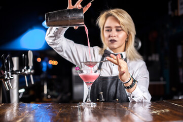 Charismatic girl bartender formulates a cocktail