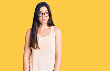 Obraz premium Young beautiful caucasian woman wearing casual clothes and glasses puffing cheeks with funny face. mouth inflated with air, crazy expression.