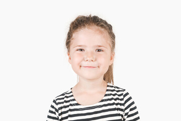 Smiling girl looking at camera. Smirking girl laughing inside and saying by her face I told you, I was right,  I knew it. Portrait of posing little girl wearing striped shirt. Isolated background.