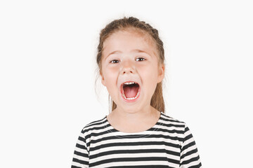 Loudly yelling or singing girl. Girl looking at camera with wide open mouth. Posing little girl wearing striped shirt. Isolated background. Announcement, attention, checkup at a dentist concept.