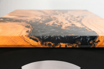 Close up of the side of a wood and epoxy table on a white backdrop