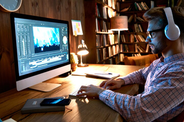 Fototapeta na wymiar Videographer editor film maker wears headphones using digital software on desktop computer editing video footage visual content working at home office using post production multimedia making montage.