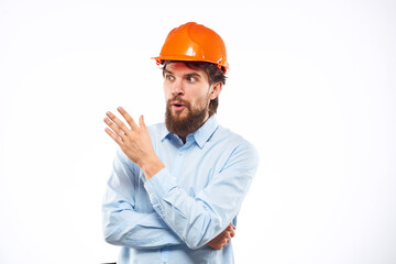 A man in an orange helmet shirt construction industry worked light background
