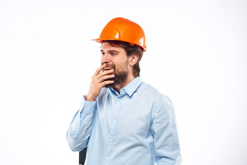 A man in an orange helmet shirt construction industry worked light background