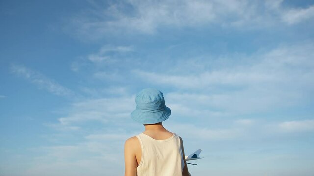 boy in a blue hat playing with airplane on sky background, boy wants to become a pilot, background of a blue sky
