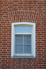 A window with a white frame on a red brick wall.
