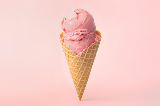 Delicious ice cream in waffle cone on pink background