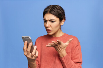 Frustrated young female expressing indignation, gesturing emotionally while reading shocking news...