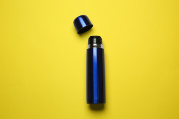 Blue metal thermos on yellow background, top view