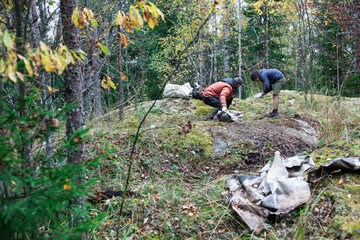 big amount of trash in forest, family father and son picking garbage away, global environment issues