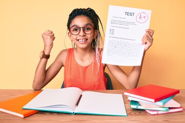 Young african american girl child with braids showing a passed exam screaming proud, celebrating victory and success very excited with raised arm