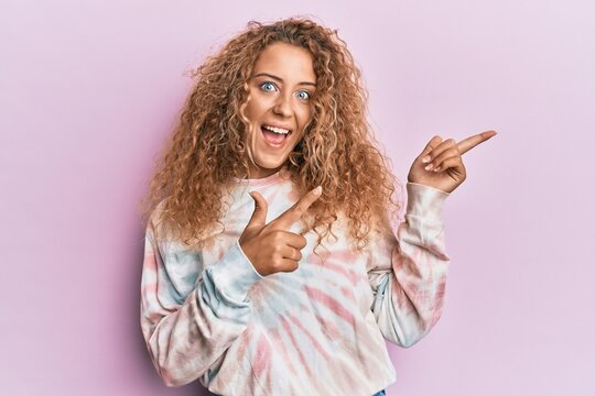 Beautiful Caucasian Teenager Girl Wearing Casual Tie Dye Sweatshirt Smiling And Looking At The Camera Pointing With Two Hands And Fingers To The Side.