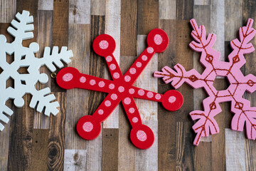 White, red and pink glitter wooden snowflakes on a brown wood plank background. Useful for rustic Christmas holiday projects