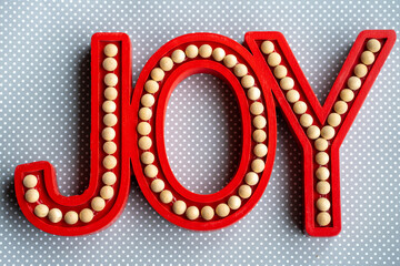 Red Joy word letters on a gray white polka dot wood background, useful for rustic Christmas holiday projects