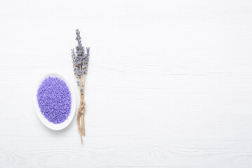 Lavender bath solt in the small bowl and dried lavender flowers on the white background.
