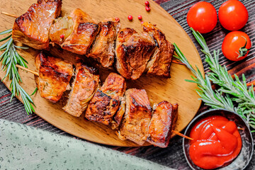 Skewers of Meat with sauce on wooden cutting board, ready to be served as summer party meal, view from above.