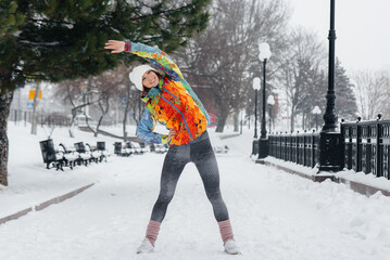 A young athletic girl does sports on a frosty and snowy day. Fitness, running
