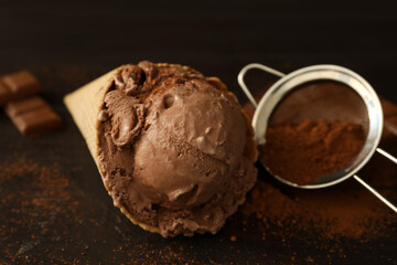 Delicious chocolate ice cream in wafer cone served on wooden table, closeup