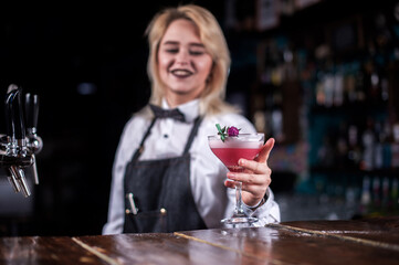 Charming woman barman makes a cocktail in the night club