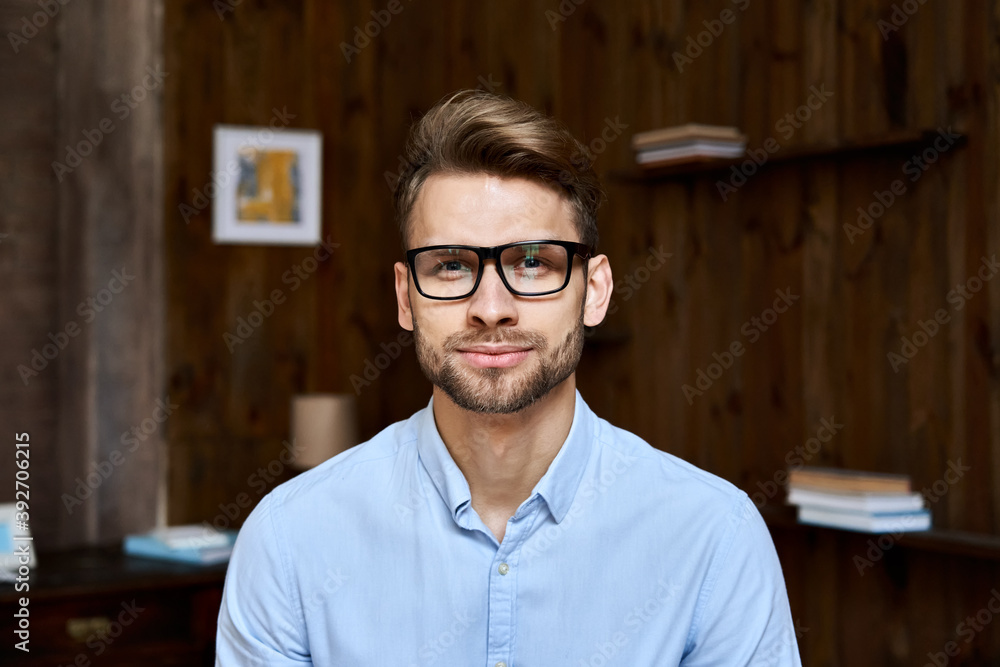 Wall mural confident young adult businessman wearing glasses looking at camera in office, charming millennial p