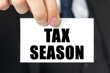 Businessman shows a card with the text TAX SEASON