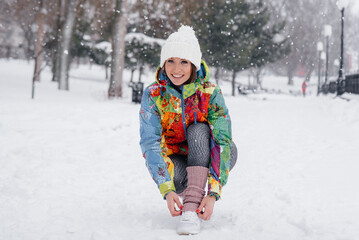A young athletic girl ties her shoes on a frosty and snowy day. Fitness, running