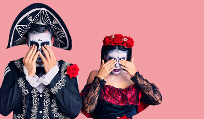 Young couple wearing mexican day of the dead costume over background rubbing eyes for fatigue and headache, sleepy and tired expression. vision problem