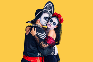 Young couple wearing mexican day of the dead costume over background hugging oneself happy and positive from backwards. self love and self care