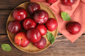 Fototapeta na wymiar Delicious ripe plums on wooden table, flat lay