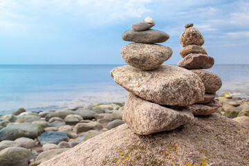 Two stones pyramid on the seashore at sunset. Pebble beach, beautiful view. Rest and seaside vacation. Concept of balanced life, harmony and relax.