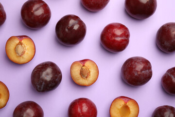 Delicious ripe plums on violet background, flat lay