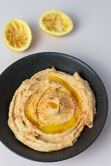 home made humous in a black bowl with lemons in background 