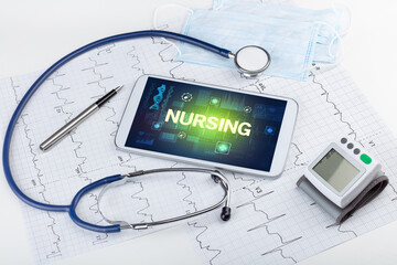 Tablet pc and medical stuff with NURSING inscription, prevention concept
