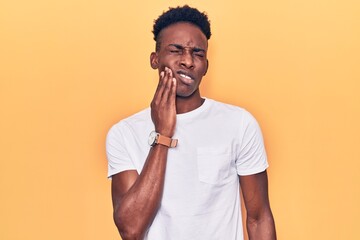 Young african american man wearing casual clothes touching mouth with hand with painful expression because of toothache or dental illness on teeth. dentist