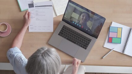Senior female recruiter talking during social distance job interview by video call. Elderly hr hiring female applicant communicating in conference virtual chat videocall meeting on laptop, top view.
