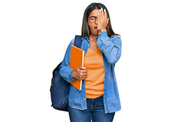 Young latin girl wearing student backpack and holding books yawning tired covering half face, eye and mouth with hand. face hurts in pain.