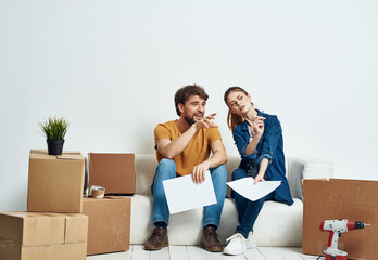 Young couple boxes with things on moving room interior