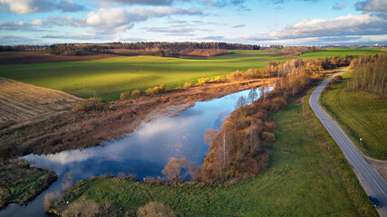 Fototapeta na wymiar Beautiful green field. Winter crops. Lake with blue sky reflection