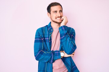 Young handsome man wearing casual clothes looking stressed and nervous with hands on mouth biting...