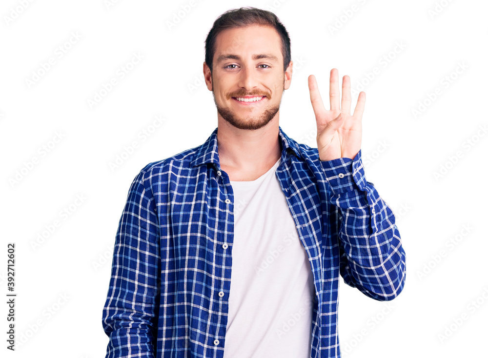 Wall mural Young handsome caucasian man wearing casual clothes showing and pointing up with fingers number four while smiling confident and happy.